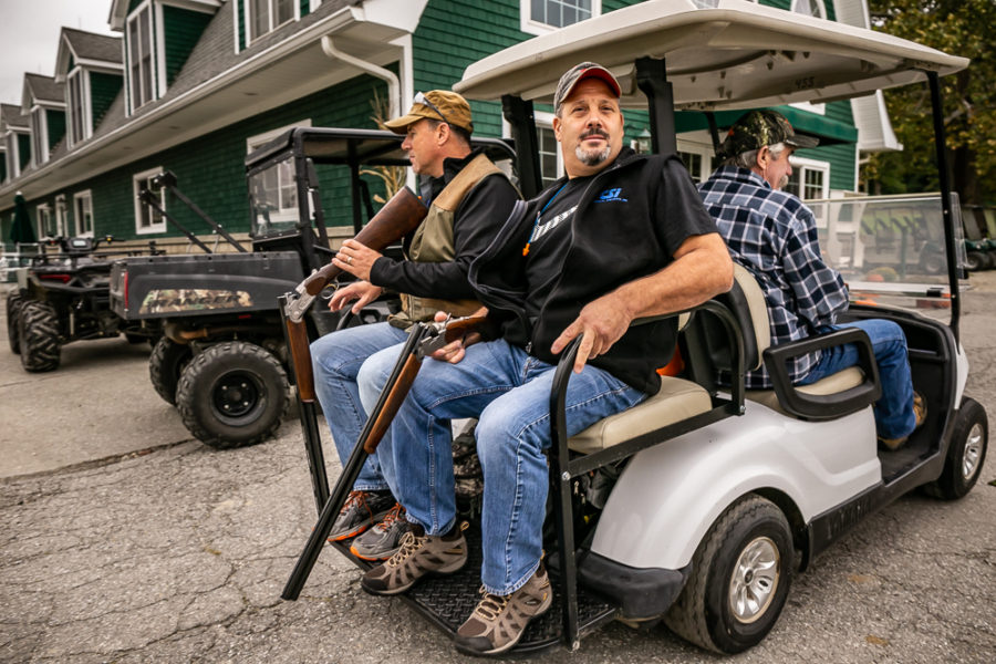 Three men with shotguns on a golf cart