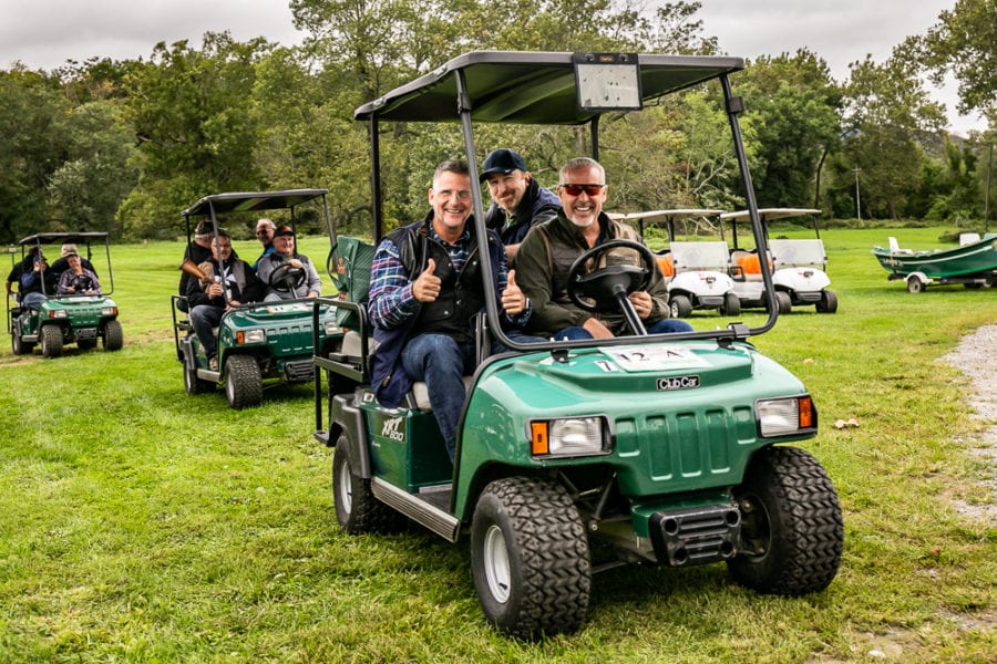 Three men giving thumbs up in golf cart
