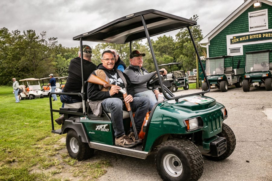 Two men riding golf cart near clubhouse
