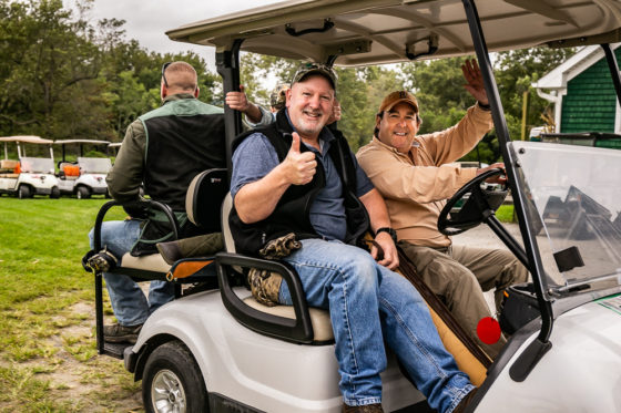 Two men smiling thumbs up in golf cart