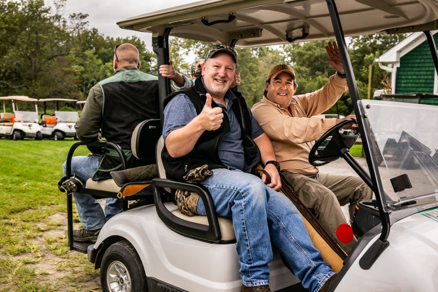 Two men smiling thumbs up in golf cart