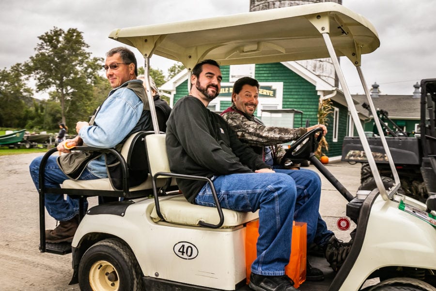 Three men smiling while seated in golf cart