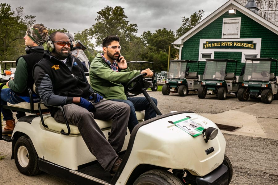 Three men in golf cart by preserve