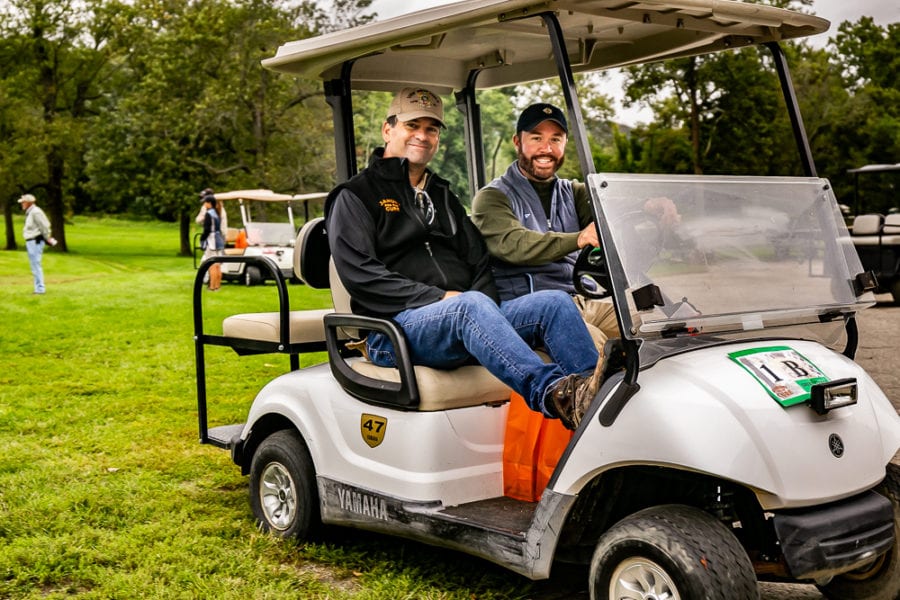 Two smiling men in a golf cart