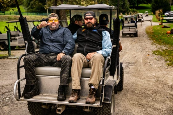 Two men riding in golf cart outdoors