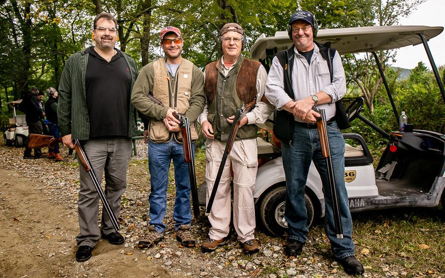 Four men posing with shotguns near golf cart
