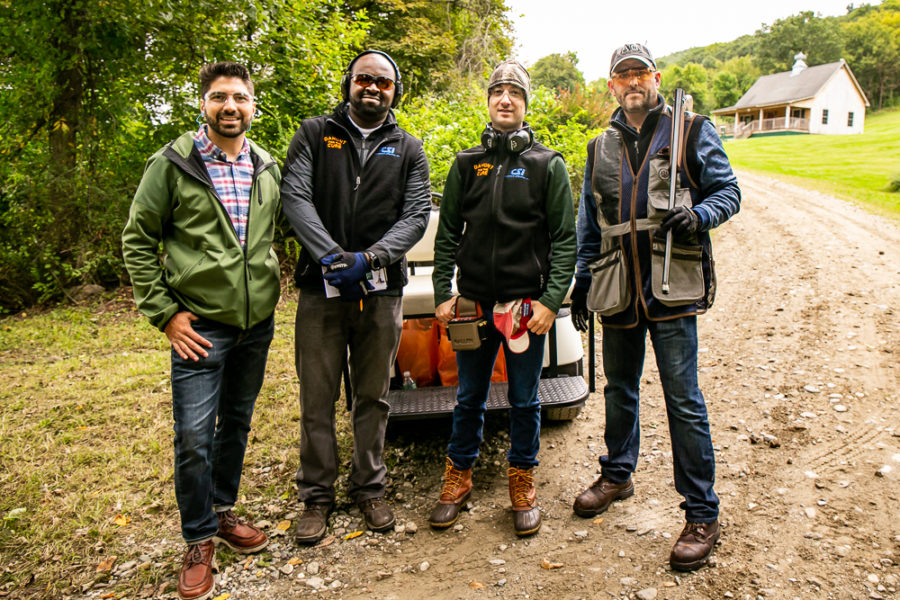 Four men posing outdoors with shooting gear