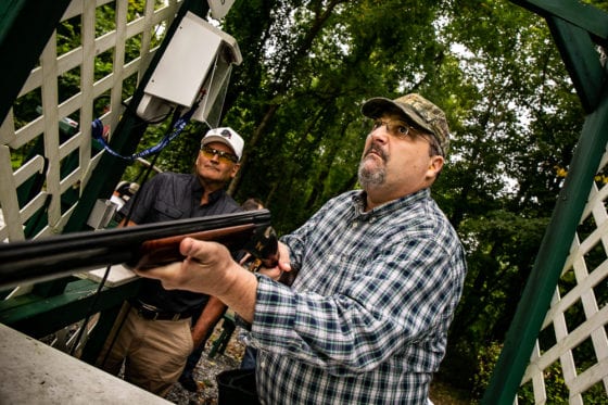 Man aiming shotgun at outdoor clay shooting range