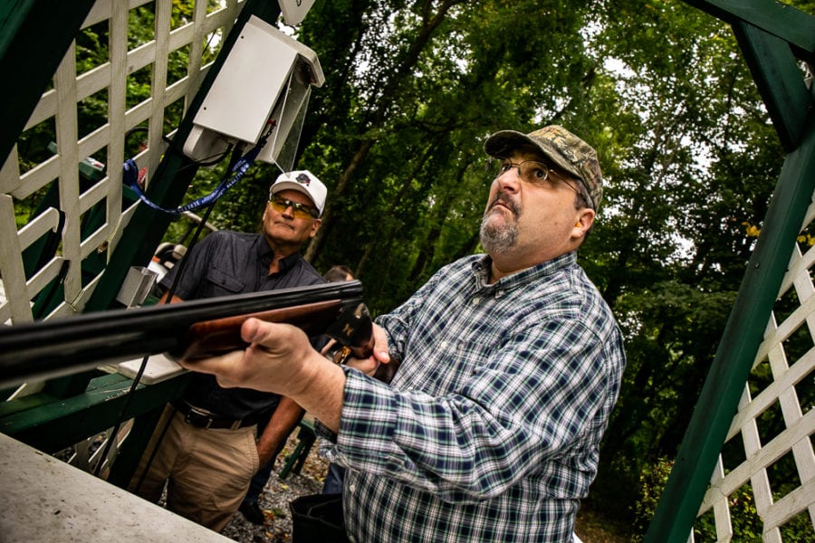 Man aiming shotgun at outdoor clay shooting range