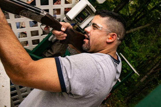 Man firing shotgun at outdoor shooting range