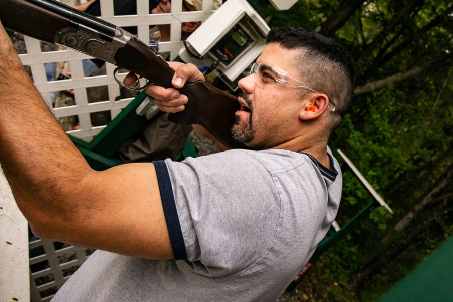 Man firing shotgun at outdoor shooting range