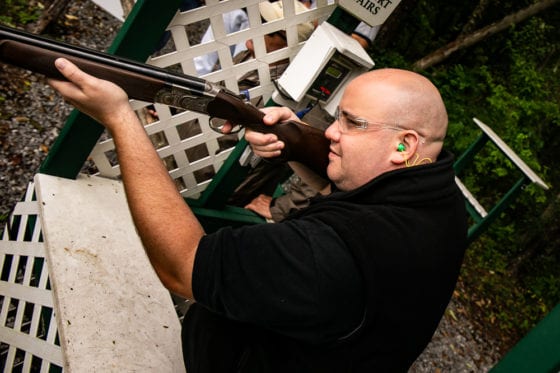 Shooter aiming shotgun at outdoor shooting range