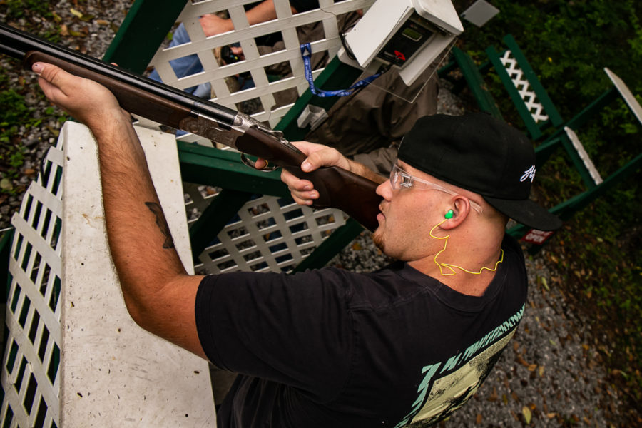 Person aiming shotgun at clay target range