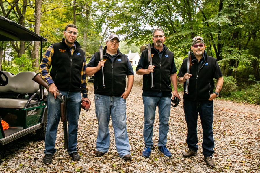 Four men holding shotguns on wooded path