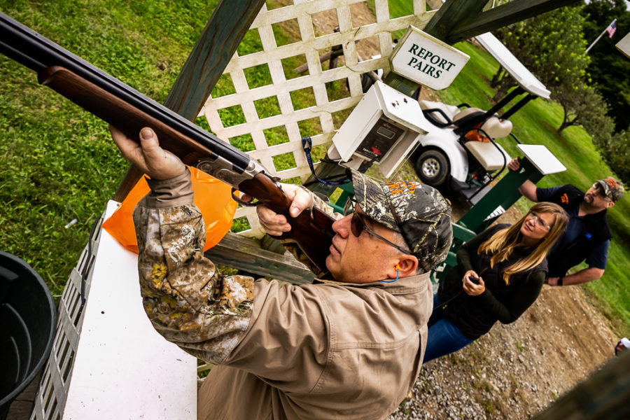 Man aiming shotgun at outdoor shooting range