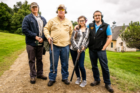 Four people posing with shotguns and ear protection