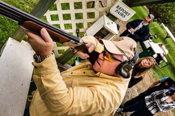 Person aiming shotgun at outdoor shooting range