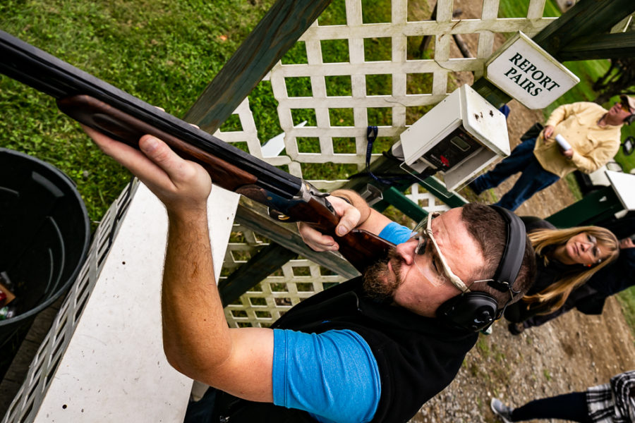 Man aiming shotgun at clay shooting station