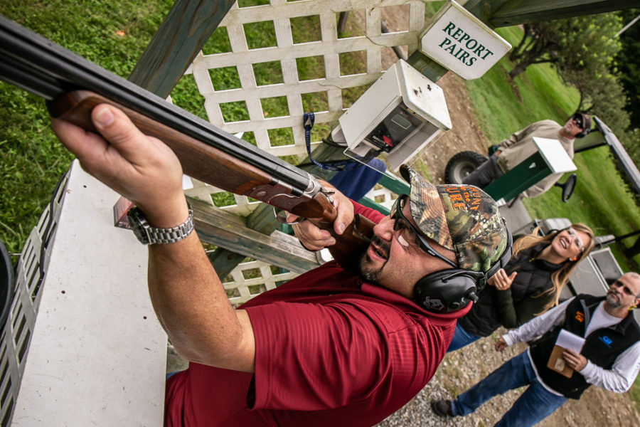 Man aiming shotgun at outdoor shooting range