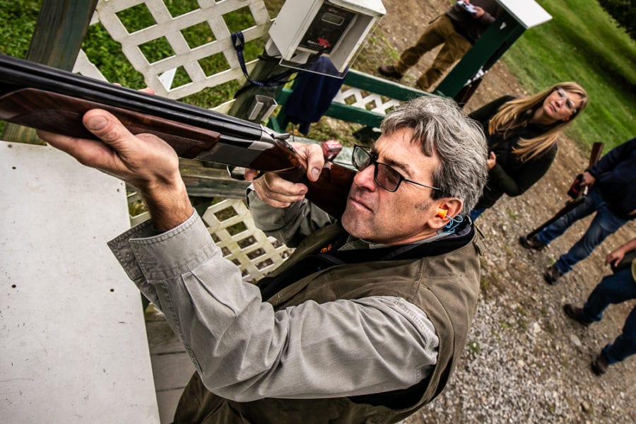 Man aiming shotgun at outdoor shooting range
