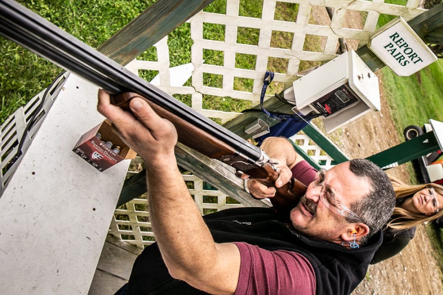 Man aiming shotgun at outdoor shooting range