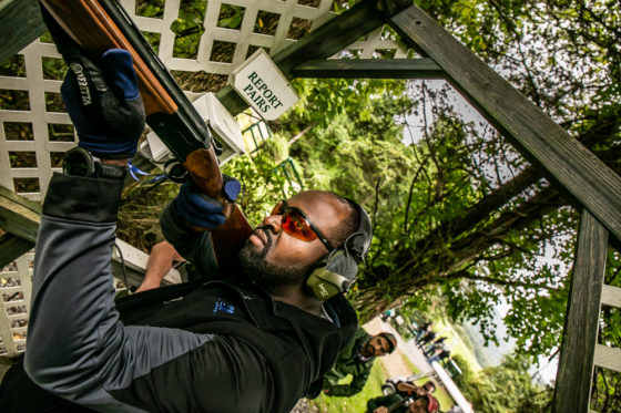Man aiming shotgun at outdoor shooting range