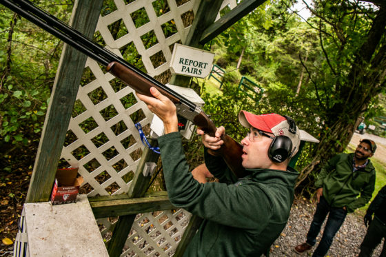 Shooter aiming shotgun at wooded outdoor range