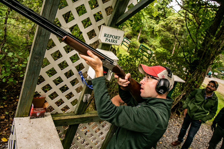 Shooter aiming shotgun at wooded outdoor range