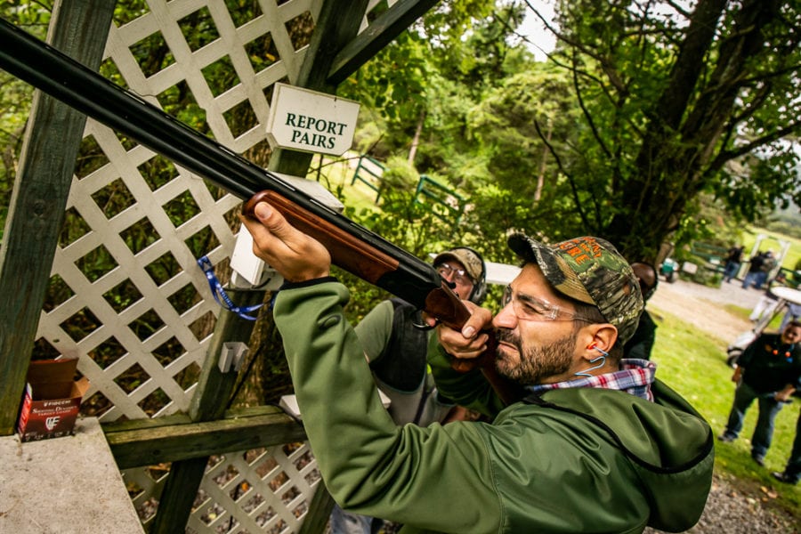 Man aiming shotgun at outdoor shooting range
