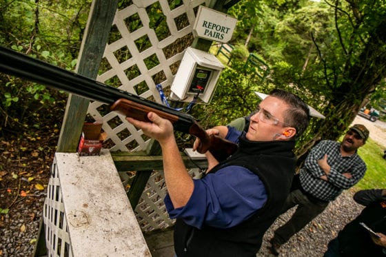 Man aiming shotgun at outdoor shooting range