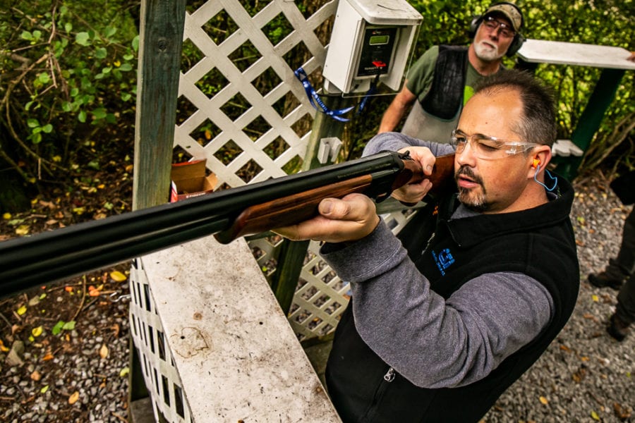Man shooting shotgun at outdoor clay range