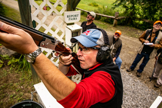 Man aiming shotgun at trap shooting range