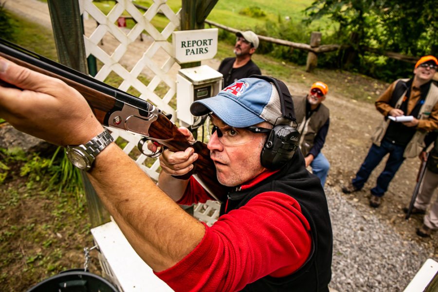 Man aiming shotgun at trap shooting range