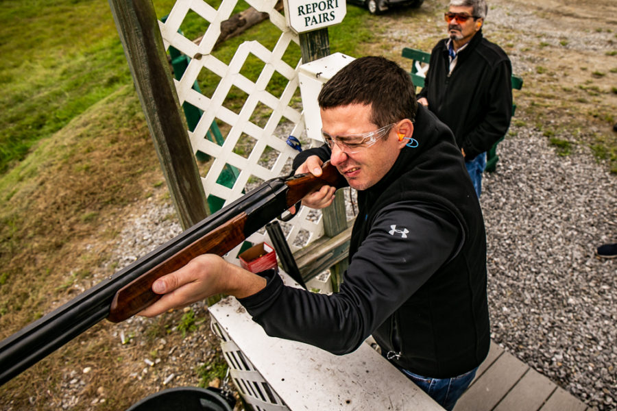 Man aiming shotgun at outdoor trap shooting range