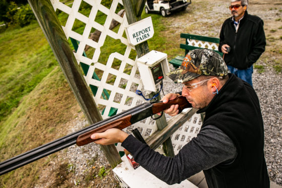 Shooter aiming shotgun at outdoor shooting range