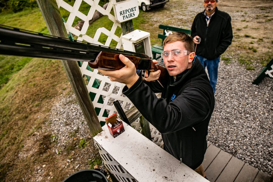 Young shooter aiming shotgun at shooting range