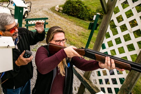 Woman aiming shotgun at outdoor shooting range