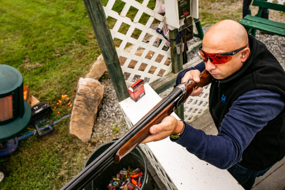 Person aiming shotgun at clay shooting range