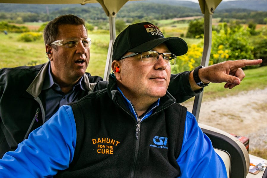 Two men in golf cart, one pointing