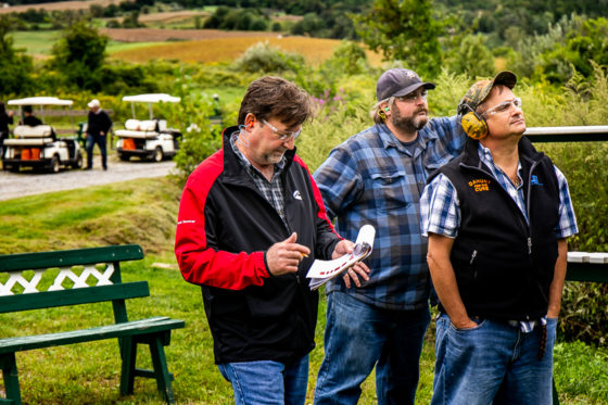 Three men standing outdoors near golf carts