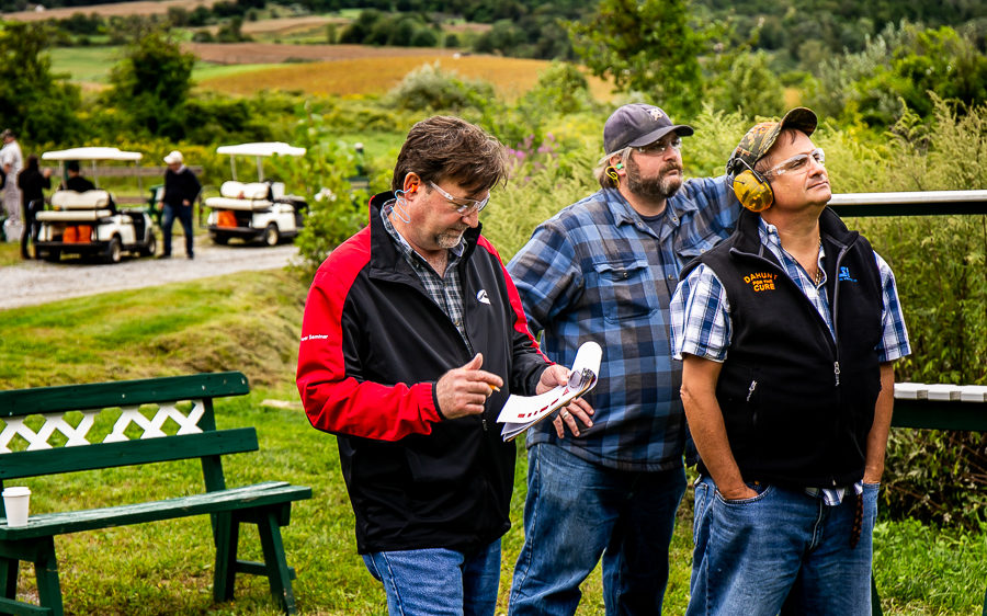 Three men standing outdoors near golf carts