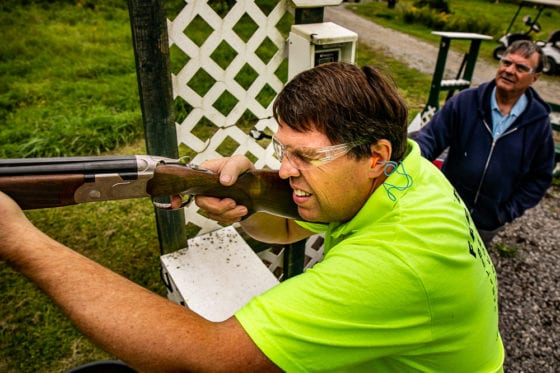 Man firing shotgun at outdoor shooting range