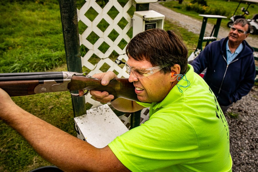 Man firing shotgun at outdoor shooting range