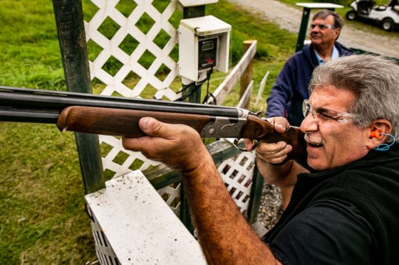 Man aiming shotgun at outdoor shooting range