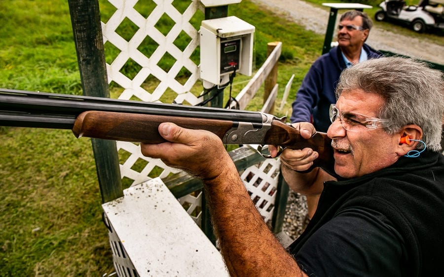 Man aiming shotgun at outdoor shooting range