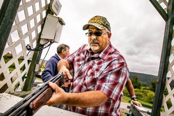Man aiming shotgun at outdoor shooting range