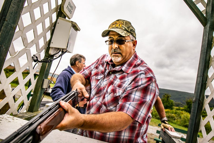 Man aiming shotgun at outdoor shooting range