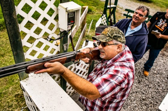Man aiming shotgun at outdoor shooting range