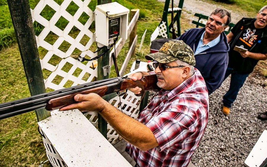 Man aiming shotgun at outdoor shooting range