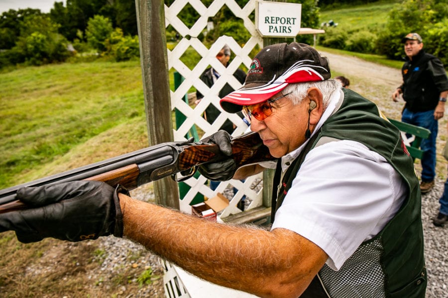 Man aiming shotgun at outdoor shooting range